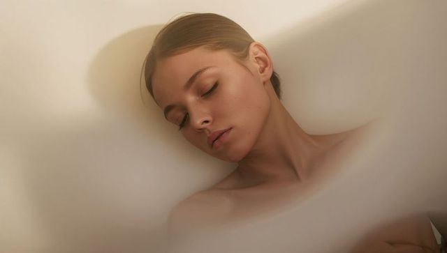 Serene woman closing eyes in soft veil lighting, bare-shoulder beauty portrait for skincare