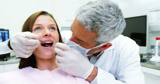Dentist examining a female patient with dental tools at dental clinic 4k