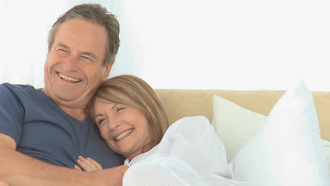 Happy Senior Couple Relaxing on Comfortable Bed