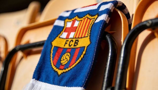 Draping fc barcelona supporter scarf over tan stadium seat showing fcb crest and texture