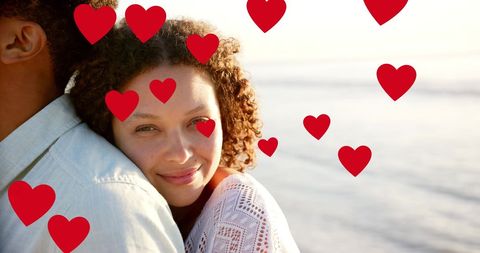 Couple Embracing Tenderly with Red Hearts at Beach