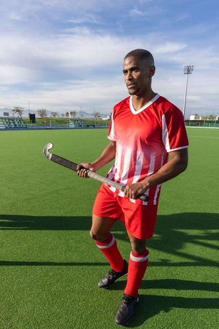 Focused athlete standing on hockey field holding stick, ready for action