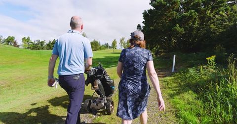Mother and son walking on golf course in golf attire