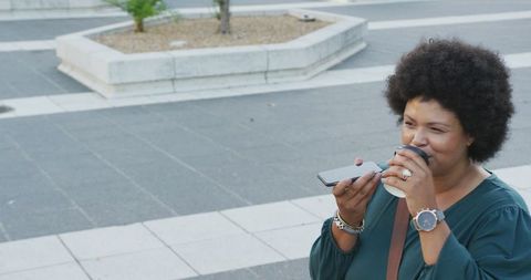 Smiling woman engaging in mobile communication with coffee in hand