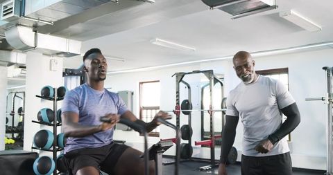 African American Trainer Guides Trainee on Rowing Machine