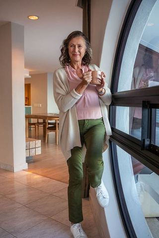 Relaxed senior woman enjoying coffee at home near window