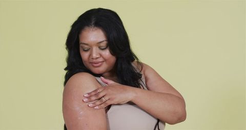 Confident Woman Applying Skincare Cream in Minimalist Setting
