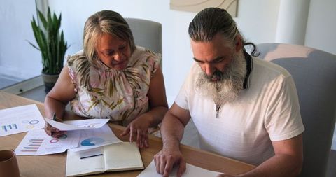 Senior couple reviewing financial documents at home with technology