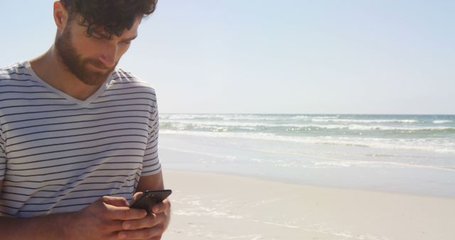 Young Man Focusing on Smartphone on Sandy Beach Location - Download Free Stock Images Pikwizard.com