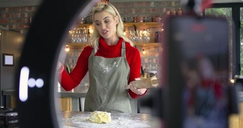 Home baker filming holiday baking tutorial with rolling pin, ring light and rustic kitchen