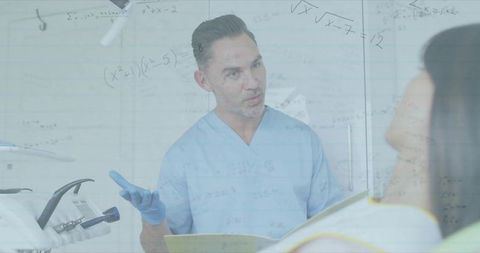 Dentist explaining treatment plan to patient while reviewing chart in dental clinic