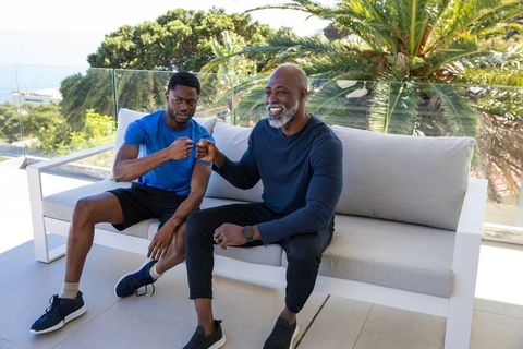 Two men in sportswear fist bumping on stylish terrace