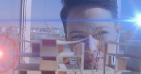 Focused female architect contemplating an intricate architectural model