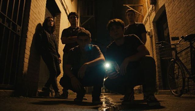 Teen crew crouching in moody urban alley holding flashlight, cinematic night backstreet drama