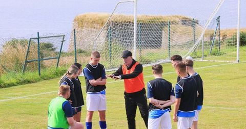 Soccer coach giving strategy talk to young players on field