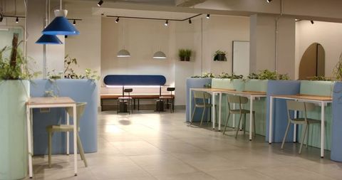 Pastel coworking lounge with private booths, wooden desks and hanging pendant lights