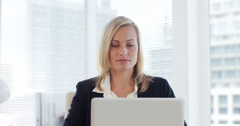 Focused Businesswoman in Modern Office Working on Laptop