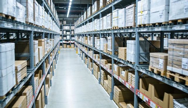 Empty warehouse aisle featuring industrial metal racking and organized cardboard pallets