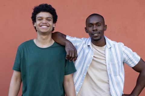 African american male friends smiling and posing together against terracotta wall