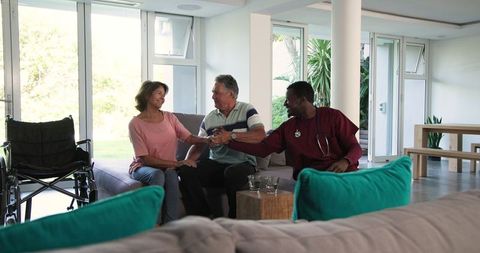 Senior Couple Enjoying Visit with Caregiver in Modern Home