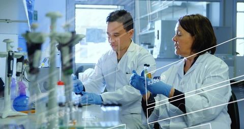 Researchers pipetting at lab bench with micropipette for collaborative clinical research