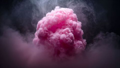 Billowing pink smoke cloud backlit on dark background for dramatic abstract visuals
