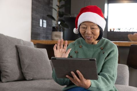 Senior Woman in Santa Hat Chatting on Tablet During Holidays