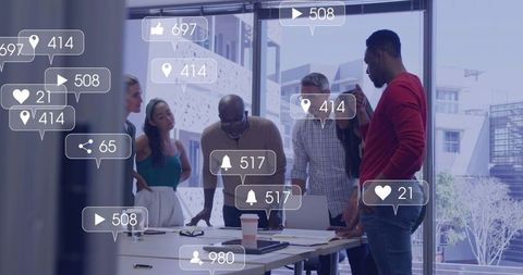 Team collaborating on marketing layouts with social media engagement icons in modern office