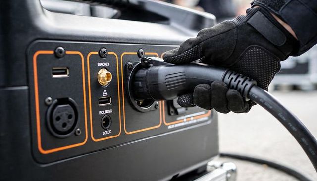 Technician plugging heavy-duty power cable into portable generator panel closeup