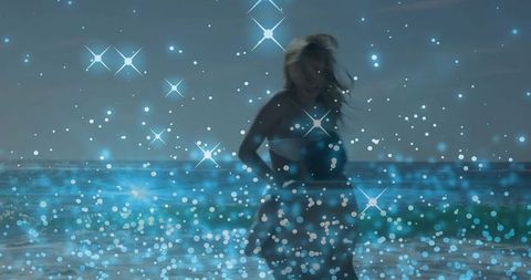 Backlit Woman Wading in Twilight Ocean Wearing Strapless Dress with Blue Bokeh Sparkle