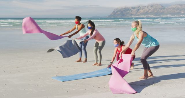 Diverse group of women preparing for beach yoga session with mats - Download Free Stock Images Pikwizard.com