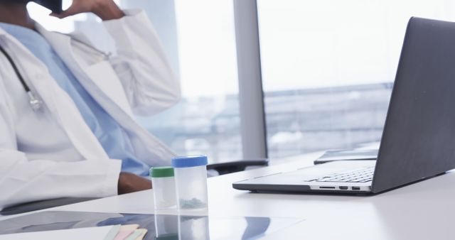 Doctor in office on phone with laptop and medical specimens - Download Free Stock Images Pikwizard.com