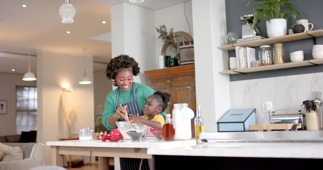 Mother and young son baking together at home in a modern kitchen. Both are engaged in preparing ingredients with smiles, emphasizing family bonding and teamwork. Suitable for content related to family activities, parenting, home life, cooking, and happy moments.