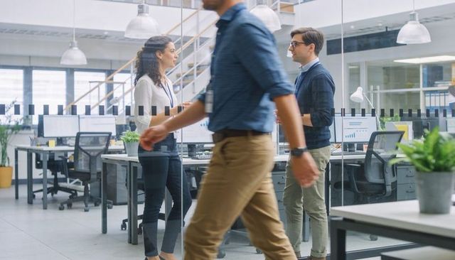 Business team collaborating in modern open-plan office reviewing charts near glass partition