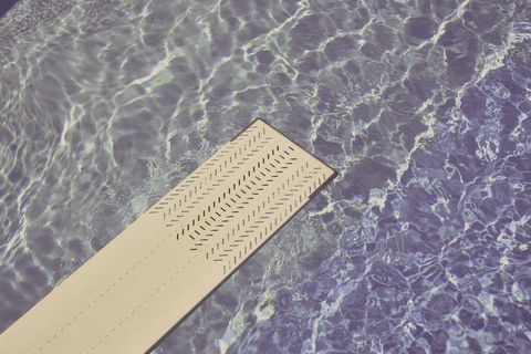 Diving board extending over sparkling blue pool water