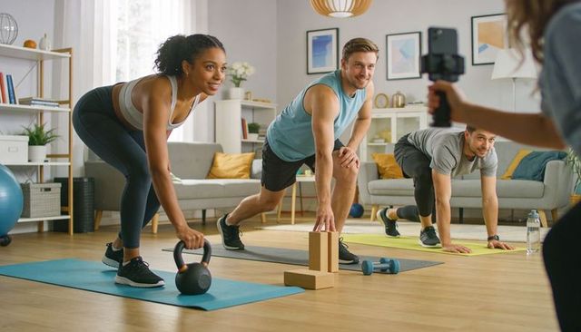 Group home workout streaming kettlebell lunges and plank exercises with smartphone filming