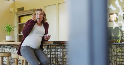 Pregnant Woman Enjoying Ice Cream in Modern Kitchen Area