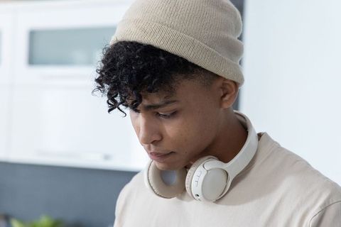 Young african american man standing in contemporary kitchen wearing beanie and headphones