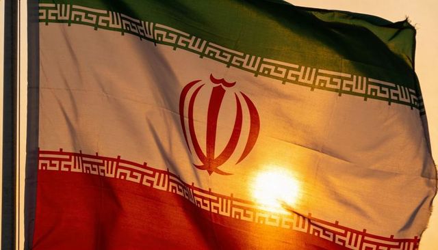Iranian flag waving at sunset backlit emblem and kufic border