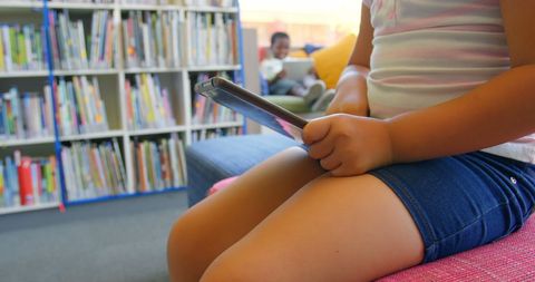Schoolchild Using Tablet in Modern Library Setting