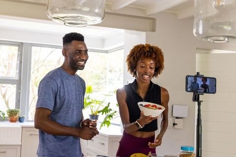 African american couple filming healthy breakfast bowl in bright sunlit home kitchen vlog