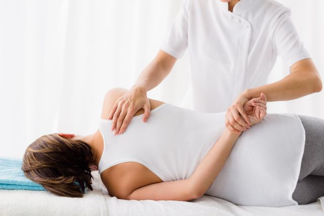 Masseur giving massage to woman at spa