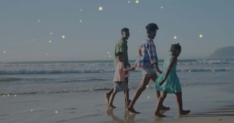 Family of Four Walking Along Beach Under Clear Sky