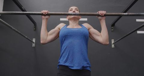 Athletic Woman Performing Chin-ups in Gym for Strength Training