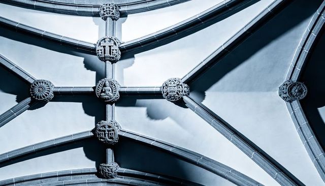Gothic ribbed vault showing carved bosses and intersecting stone ribs with dramatic shadows