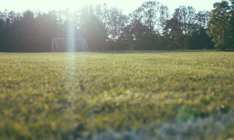 Sunlight basking soccer goal on quiet grass field with morning lens flare