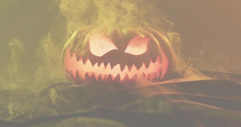Glowing jack-o'-lantern emitting eerie smoke over draped tabletop for halloween display