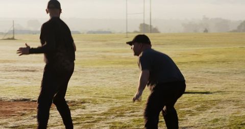 Mature Men Practicing Football Drills on Grass Field at Sunrise