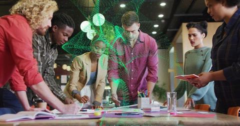 Creative team collaborating around table with green ar overlay in modern office