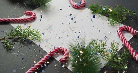 Festive candy cane flat lay with confetti and evergreen sprigs for holiday card design